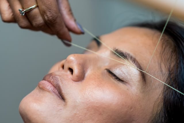 A woman having her eyebrows threded