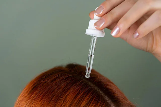 A red-haired woman receiving biotin scalp treatment
