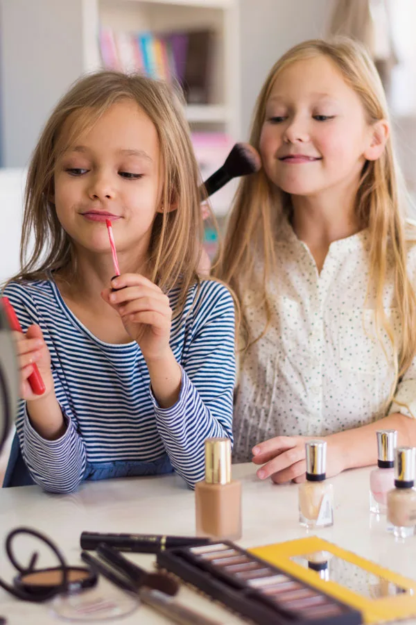Two young girls applying makeup to themselves
