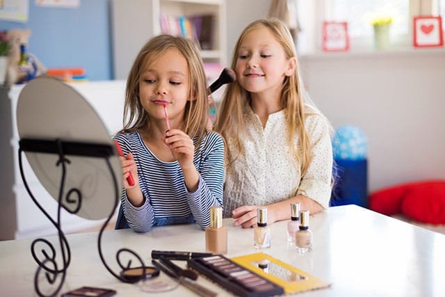 Two young girls applying makeup to themselves